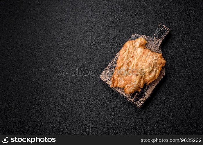 Delicious fried chicken chop or pork meat fried breaded with salt, spices and herbs on a dark concrete background