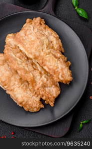 Delicious fried chicken chop or pork meat fried breaded with salt, spices and herbs on a dark concrete background