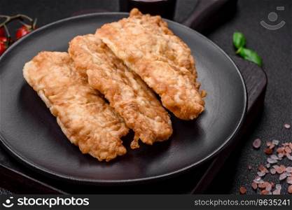 Delicious fried chicken chop or pork meat fried breaded with salt, spices and herbs on a dark concrete background