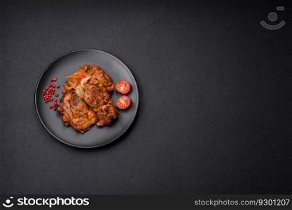 Delicious fried chicken in sauce with onions, salt, spices and herbs on a dark concrete background