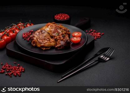 Delicious fried chicken in sauce with onions, salt, spices and herbs on a dark concrete background