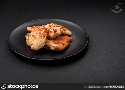 Delicious fried chicken meat chops with spices, salt and herbs on a dark concrete background