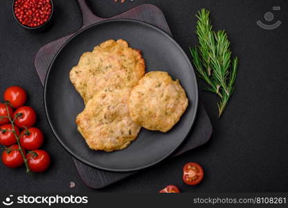 Delicious fried chopped fillet pancakes with spices, salt and herbs on a dark concrete background
