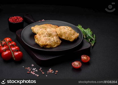 Delicious fried chopped fillet pancakes with spices, salt and herbs on a dark concrete background