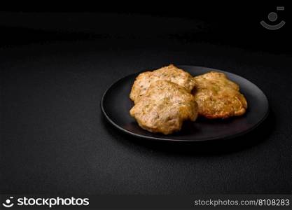 Delicious fried chopped fillet pancakes with spices, salt and herbs on a dark concrete background