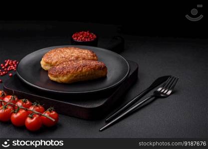 Delicious fried cutlets or meatballs from minced fish with spices and herbs on a dark concrete background
