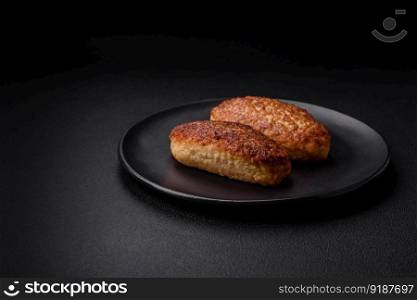 Delicious fried cutlets or meatballs from minced fish with spices and herbs on a dark concrete background