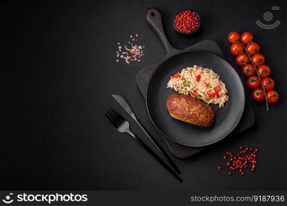 Delicious fried cutlets or meatballs of minced fish with rice, vegetables, spices and herbs on a dark concrete background