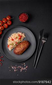 Delicious fried cutlets or meatballs of minced fish with rice, vegetables, spices and herbs on a dark concrete background