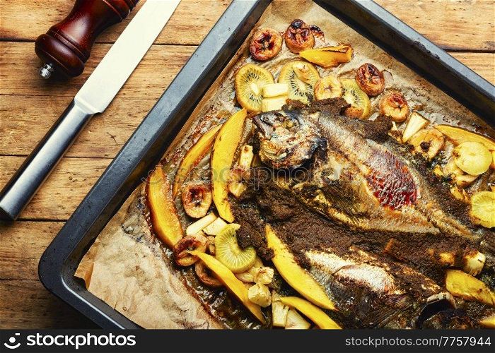 Delicious fried fish dorada with fruits and spices.. Baked gilthead fish in fruit.