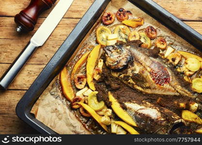 Delicious fried fish dorada with fruits and spices.. Baked gilthead fish in fruit.