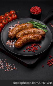 Delicious fried grilled sausages with salt, spices and herbs on a dark concrete background