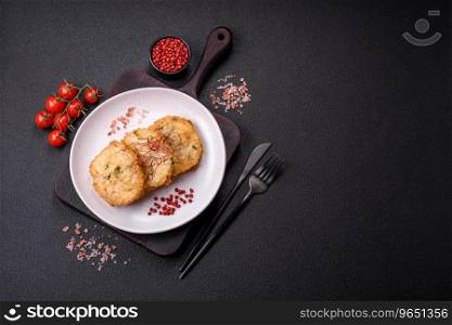 Delicious fried minced fish cutlets or meatballs with salt, spices and herbs on a dark concrete background