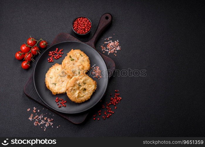 Delicious fried minced fish cutlets or meatballs with salt, spices and herbs on a dark concrete background