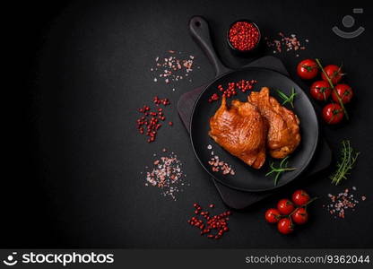 Delicious fried or smoked chicken thighs grilled with spices and herbs on a dark concrete background