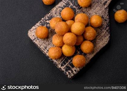 Delicious fried potato balls with breaded mozzarella, salt, spices and herbs on a dark concrete background