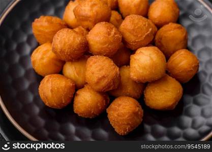 Delicious fried potato balls with breaded mozzarella, salt, spices and herbs on a dark concrete background