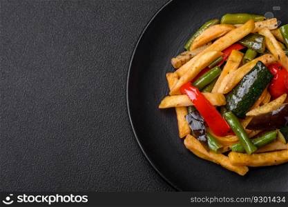 Delicious fried potatoes with bell peppers, as¶gus beans, sa<and sπces in a plate on a dark concrete background