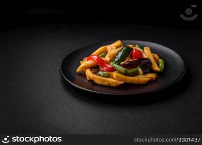 Delicious fried potatoes with bell peppers, asparagus beans, salt and spices in a plate on a dark concrete background