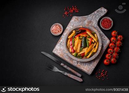 Delicious fried potatoes with bell peppers, asparagus beans, salt and spices in a plate on a dark concrete background