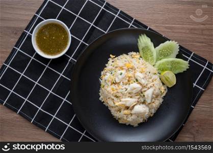 Delicious Fried rice with crab meat, egg, garlic, cucumber, lemon. Thai food called Khao pad poo. top view on wooden background. flat lay.