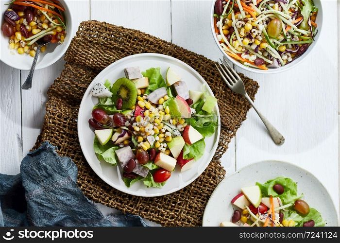 Delicious fruit salad and different fruits on the white table, healthy food concept