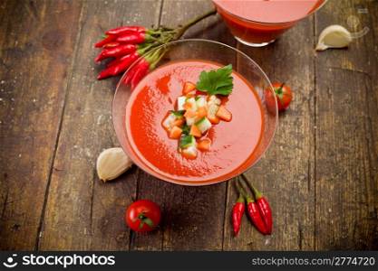 Delicious gazpacho on wooden table with fresh vegetables