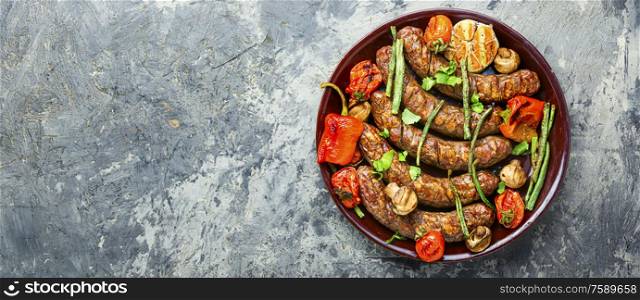 Delicious german sausages with grilled mushrooms and tomatoes.BBQ with sausage. Sausages fried with vegetable