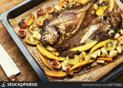 Delicious gilthead or dorada roasted with pineapple, mango, kiwi and banana.. Baked fish with pineapple, mango and kiwi.