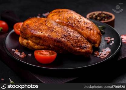 Delicious grilled chicken fillet with spices and herbs on a dark concrete background
