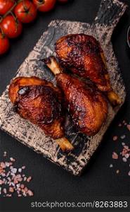 Delicious grilled chicken legs with spices and herbs in teriyaki sauce on a dark concrete background