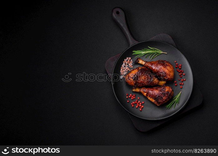 Delicious grilled chicken legs with spices and herbs in teriyaki sauce on a dark concrete background