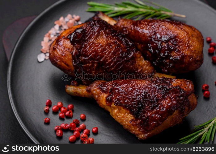 Delicious grilled chicken legs with spices and herbs in teriyaki sauce on a dark concrete background