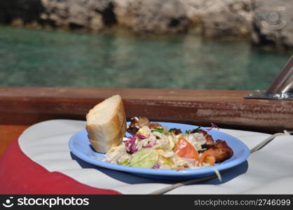 delicious grilled chicken on spit, salad and bread (lunch on board of a cruising boat)