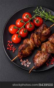 Delicious grilled chicken, turkey or pork skewers with salt, spices and herbs on a fire on a dark concrete background