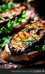 Delicious grilled eggplant sandwich. On a wooden background. High quality photo. Delicious grilled eggplant sandwich. On a wooden background.