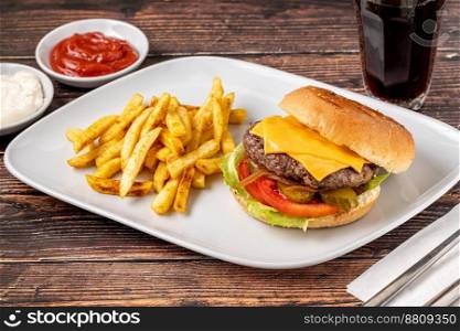 Delicious grilled homemade cheeseburger with beef, tomatoes, cheese, and lettuce on rustic wooden background