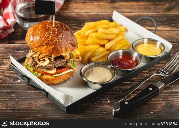 Delicious grilled homemade hamburger with beef, tomatoes, cheese, and lettuce on rustic wooden background