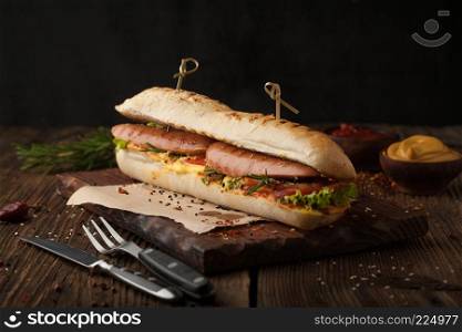 Delicious grilled hot dog with sausage and bacon, ketchup and mustard on a wooden background