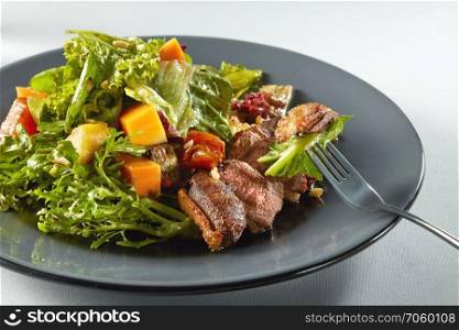 delicious, grilled meat duck with roasted pumpkin with salad on a fork. salad with pumpkin on white background