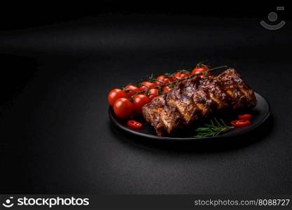 Delicious grilled pork ribs with sauce, spices and herbs on a dark concrete background