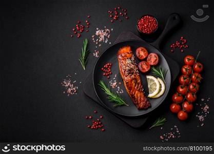 Delicious grilled red salmon fish with sauce, sesame seeds, spices and herbs on a dark concrete background