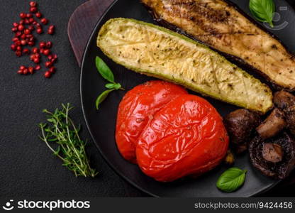 Delicious grilled vegetables zucchini, eggplant, peppers and mushrooms with salt, spices and herbs on a dark concrete background