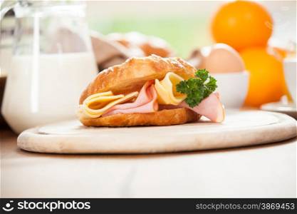 Delicious ham and cheese croissant on a wooden table