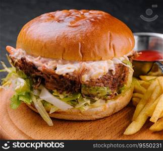 Delicious hamburger with cheese sauce and french fries on wooden table