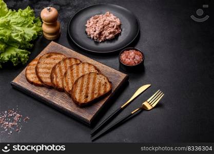 Delicious hea<hy sandwich with tuna, croutons, boi≤d egg, herbs and butter on a dark concrete background. Delicious hea<hy sandwich with tuna, croutons, boi≤d egg, herbs and butter