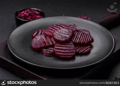 Delicious healthy boiled ruby-colored beets sliced ??on a black plate on a dark concrete background