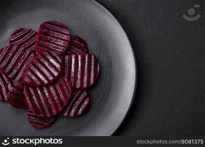 Delicious healthy boiled ruby-colored beets sliced ??on a black plate on a dark concrete background
