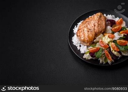 Delicious healthy breakfast consisting of chicken, rice, greens and cherry tomatoes on a black ceramic plate on a dark concrete background