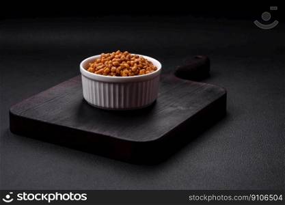 Delicious healthy canned lentils in a ceramic ribbed white bowl on a dark concrete background